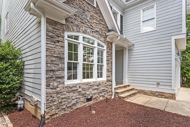 property entrance featuring stone siding and crawl space