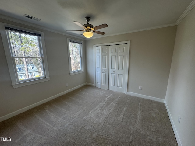 unfurnished bedroom featuring carpet floors, a closet, visible vents, ornamental molding, and baseboards