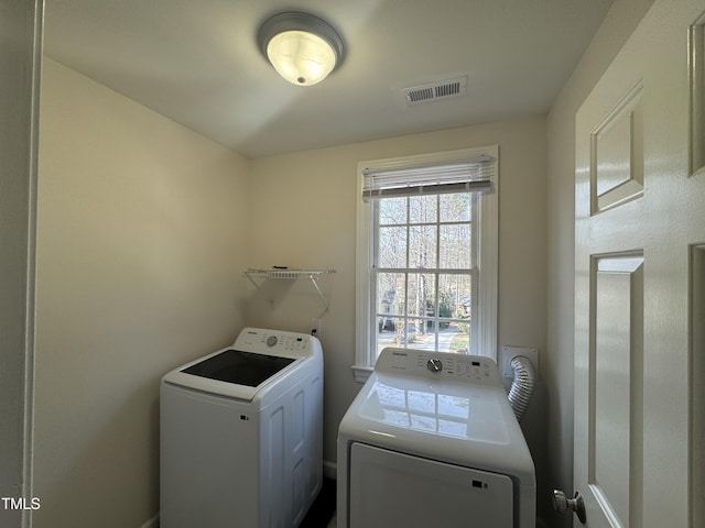 washroom with laundry area, separate washer and dryer, and visible vents