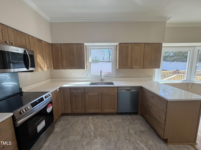 kitchen with stainless steel appliances, light countertops, a sink, and a peninsula