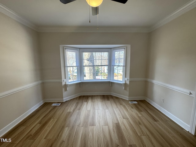 empty room with visible vents, crown molding, baseboards, and wood finished floors