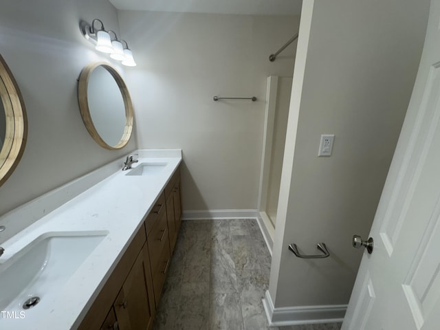 bathroom featuring double vanity, baseboards, walk in shower, and a sink