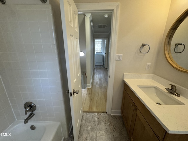 full bathroom featuring bathtub / shower combination, visible vents, vanity, ornamental molding, and washer / dryer