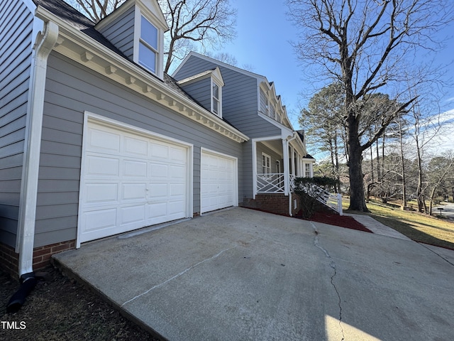 view of side of property with a porch, concrete driveway, and an attached garage