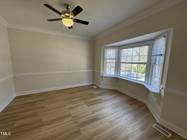 spare room with baseboards, crown molding, visible vents, and wood finished floors