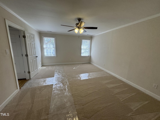 carpeted spare room featuring ornamental molding, a ceiling fan, and baseboards