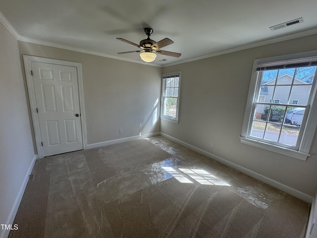 empty room with baseboards, visible vents, ceiling fan, and crown molding