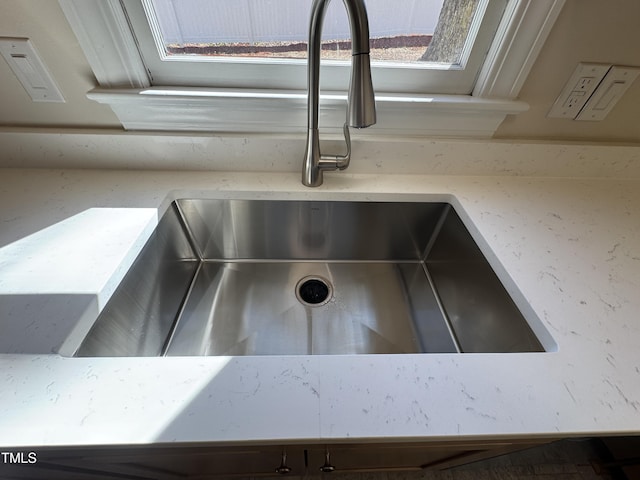 details with light stone countertops and a sink