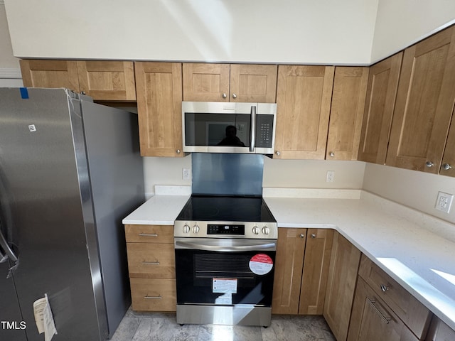 kitchen featuring brown cabinets, appliances with stainless steel finishes, and light countertops