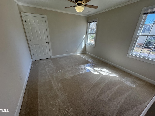 empty room with visible vents, baseboards, a ceiling fan, crown molding, and carpet flooring