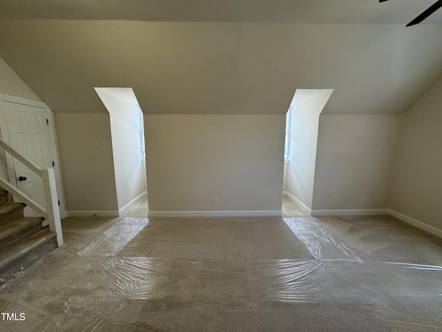 additional living space featuring stairs, baseboards, and vaulted ceiling