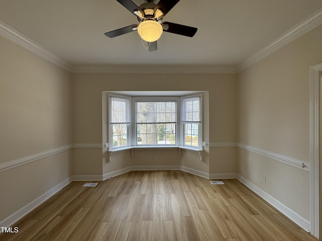 spare room featuring light wood-style floors, baseboards, visible vents, and ornamental molding