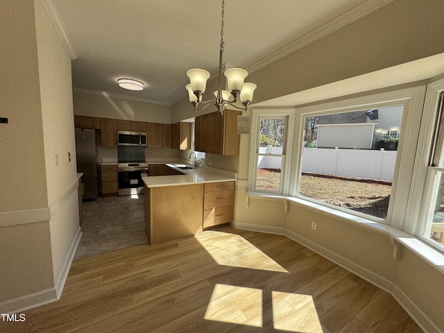 kitchen with stainless steel appliances, a sink, light countertops, ornamental molding, and light wood finished floors