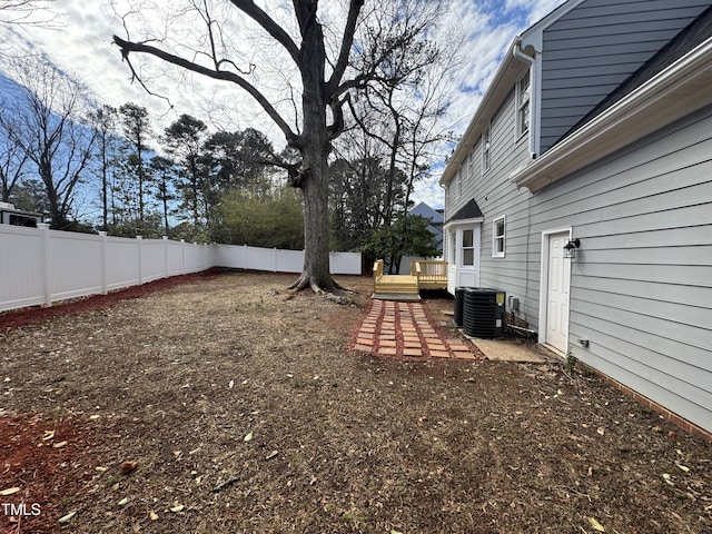 view of yard featuring a deck, a fenced backyard, and central air condition unit