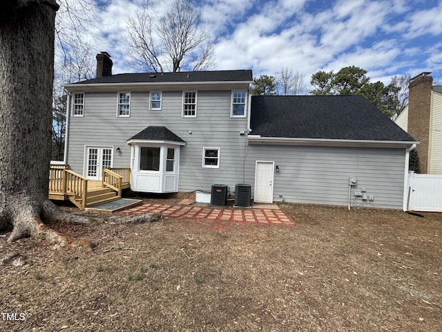 rear view of house featuring cooling unit, a shingled roof, fence, a wooden deck, and a chimney