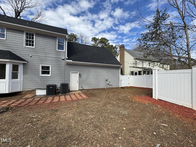 back of house with central AC, a shingled roof, and fence