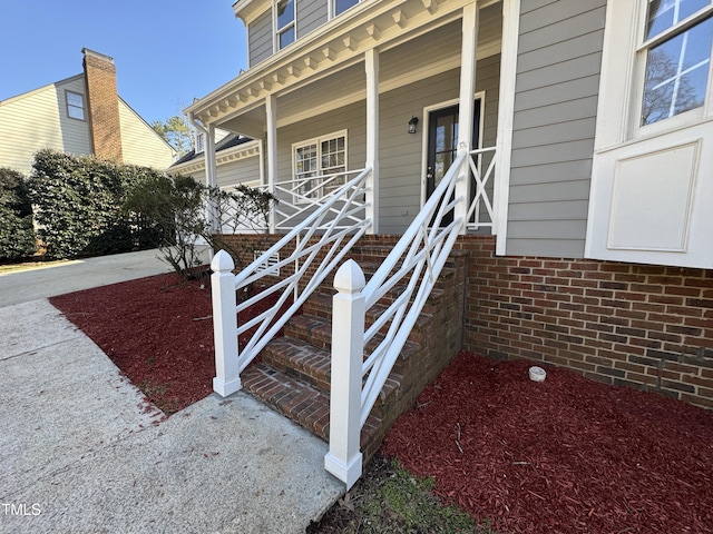 entrance to property featuring covered porch and brick siding