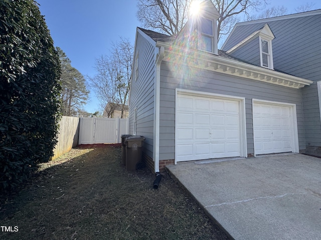 garage with driveway, fence, and a gate