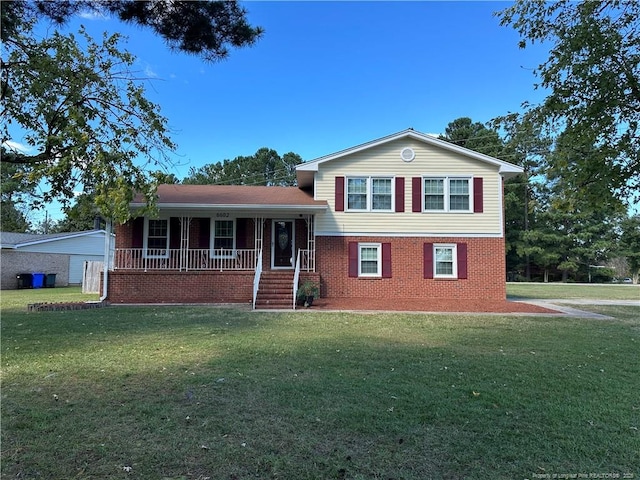 tri-level home with a porch, brick siding, and a front lawn