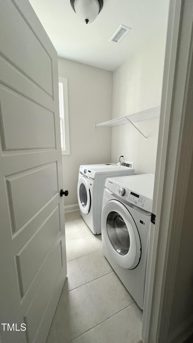 washroom with light tile patterned floors, laundry area, visible vents, baseboards, and washing machine and clothes dryer