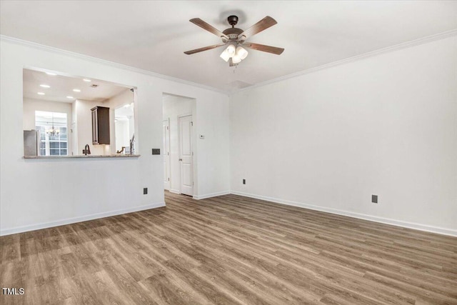 spare room with crown molding, baseboards, and wood finished floors