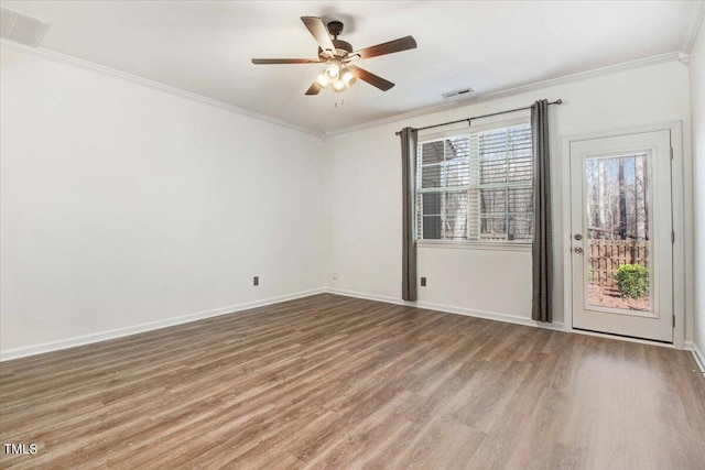 unfurnished room with baseboards, visible vents, wood finished floors, and ornamental molding