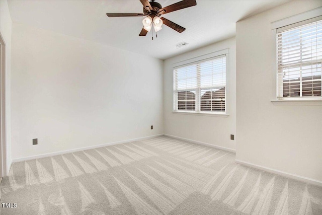 spare room featuring visible vents, baseboards, a ceiling fan, and light colored carpet