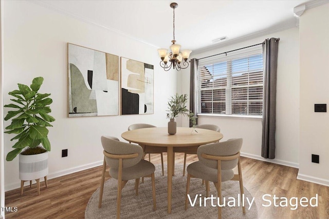 dining room with a notable chandelier, wood finished floors, visible vents, and baseboards