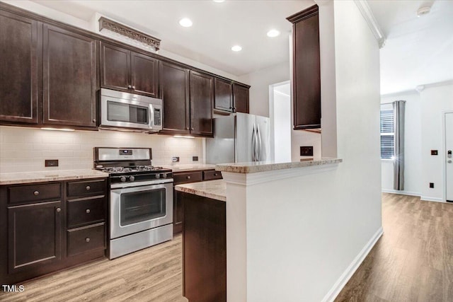 kitchen featuring stainless steel appliances, backsplash, light wood-style flooring, and light stone countertops