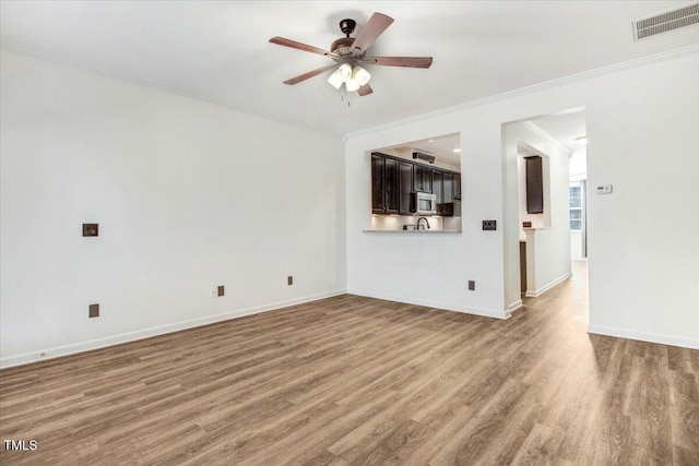 unfurnished living room featuring baseboards, wood finished floors, a ceiling fan, and crown molding