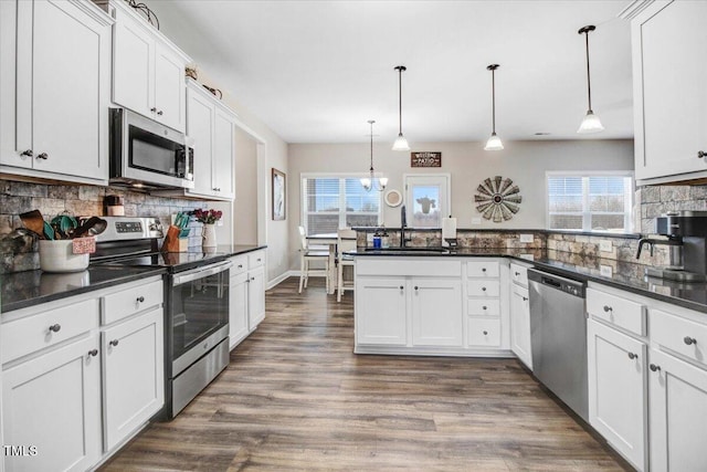301 Stonebridge Dr, Pikeville, NC 27863 - kitchen with white cabinets, dark countertops, stainless steel appliances, and decorative light fixtures