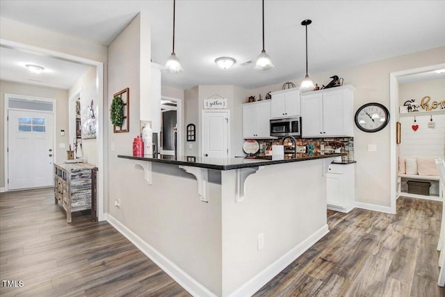 301 Stonebridge Dr, Pikeville, NC 27863 - kitchen featuring a breakfast bar area, a peninsula, white cabinets, stainless steel microwave, and pendant lighting