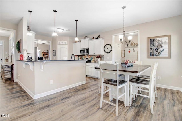 301 Stonebridge Dr, Pikeville, NC 27863 - kitchen featuring decorative light fixtures, dark countertops, stainless steel microwave, white cabinets, and a peninsula