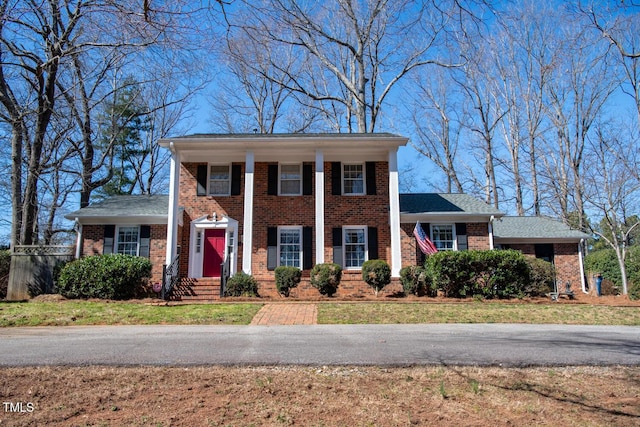 neoclassical / greek revival house with a front yard and brick siding