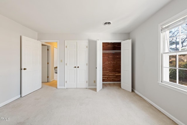 unfurnished bedroom with visible vents, baseboards, and two closets