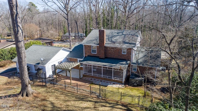 exterior space featuring brick siding, a chimney, fence private yard, and a sunroom