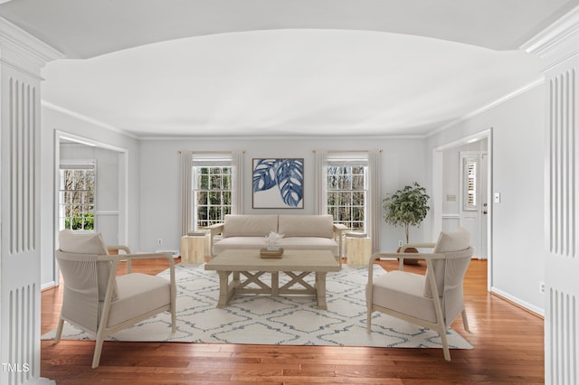 living area featuring ornamental molding, wood-type flooring, and baseboards