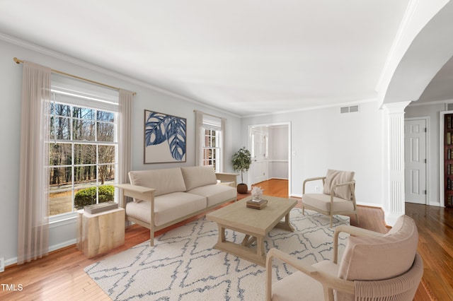 living area with ornamental molding, visible vents, ornate columns, and wood finished floors