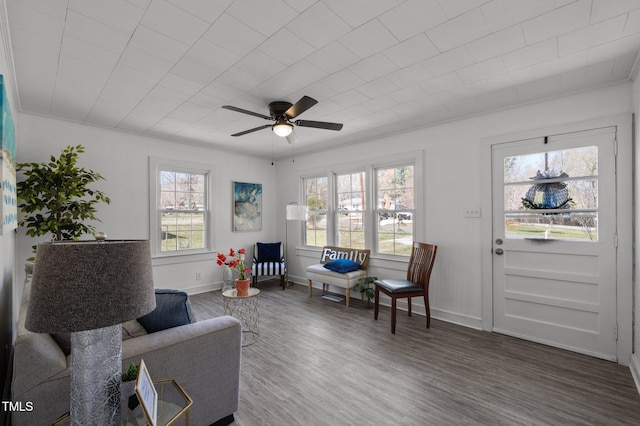 living area with a ceiling fan, baseboards, and wood finished floors