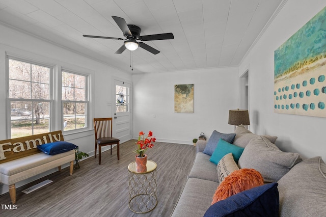 living area featuring wood finished floors, baseboards, visible vents, ceiling fan, and ornamental molding