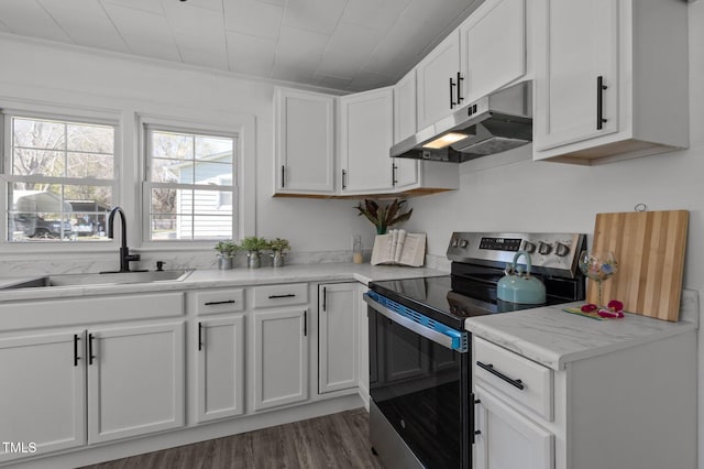 kitchen featuring light countertops, under cabinet range hood, electric range, a sink, and white cabinets