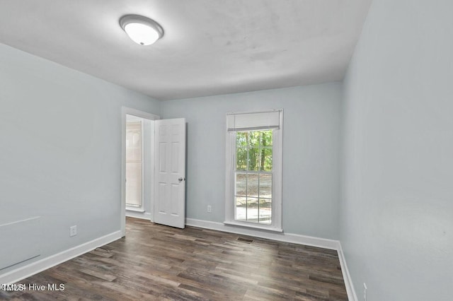 unfurnished room with visible vents, baseboards, and dark wood finished floors