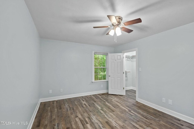 empty room with ceiling fan, baseboards, and dark wood-type flooring