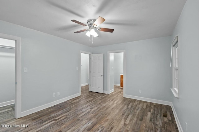 unfurnished bedroom featuring a ceiling fan, visible vents, baseboards, and dark wood-style flooring