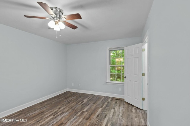 unfurnished room with a ceiling fan, baseboards, and dark wood-style flooring