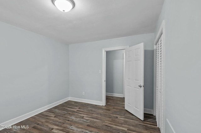 unfurnished bedroom featuring dark wood-style flooring and baseboards