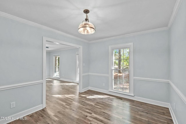 spare room featuring crown molding, wood finished floors, visible vents, and baseboards