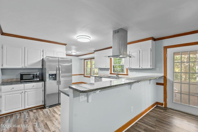 kitchen featuring appliances with stainless steel finishes, white cabinetry, island exhaust hood, and a peninsula