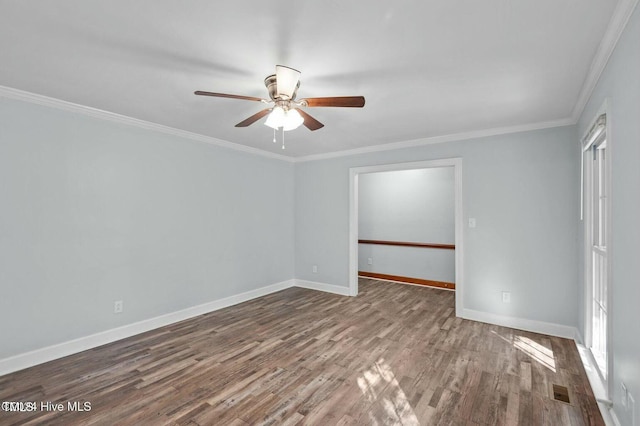 spare room featuring ceiling fan, wood finished floors, visible vents, baseboards, and ornamental molding