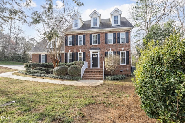 colonial home featuring crawl space, brick siding, and a front lawn